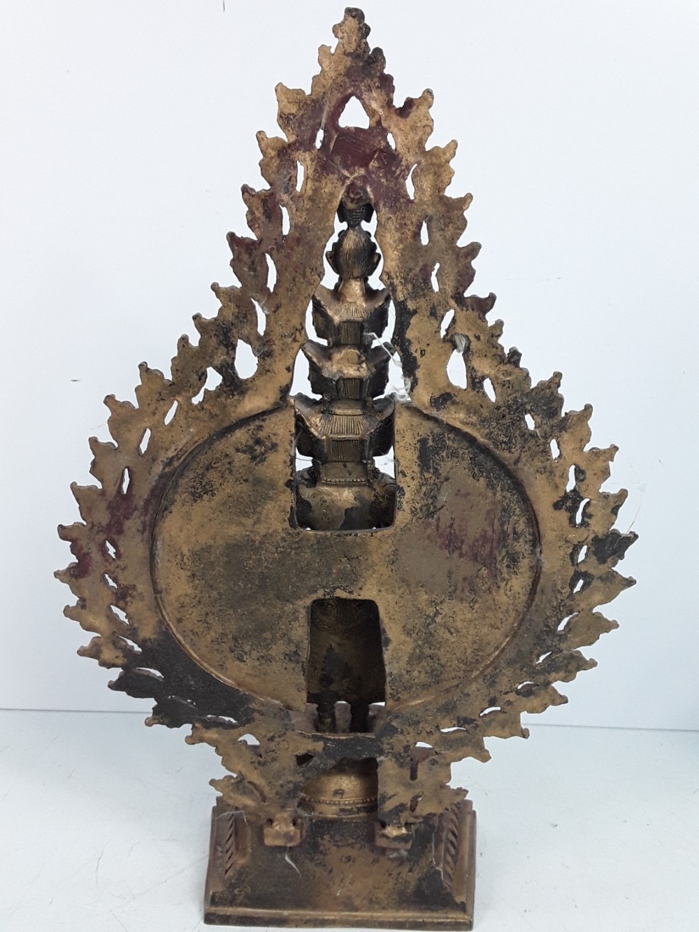 A dark bronze Tibetan sculpture depicting eleven-headed Avalokiteshvara with radiating arms set against a halo mandorla on a lotus pedestal. View IV