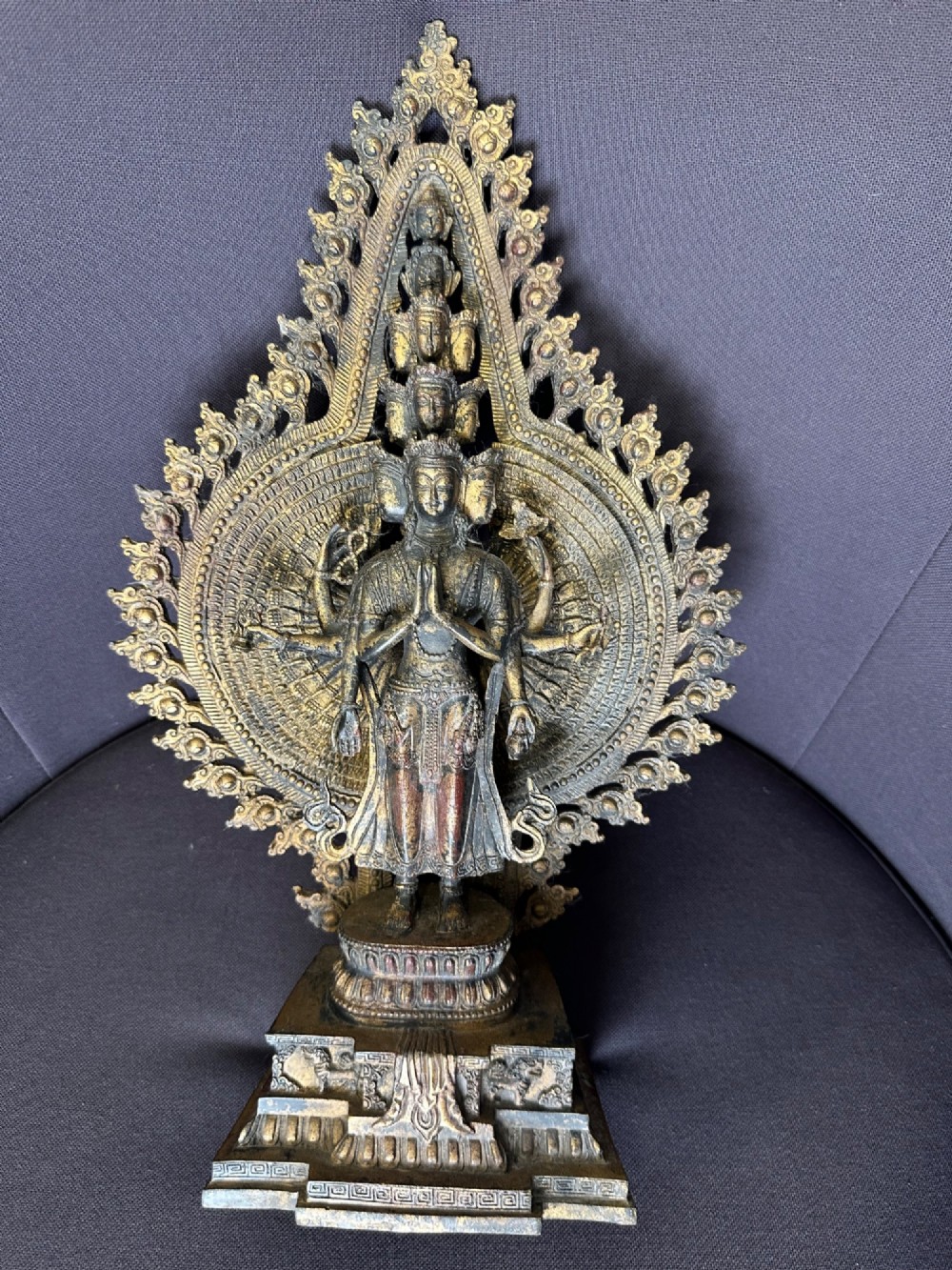 A dark bronze Tibetan sculpture depicting eleven-headed Avalokiteshvara with radiating arms set against a halo mandorla on a lotus pedestal. View VII