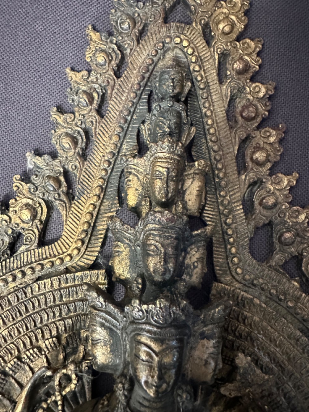 A dark bronze Tibetan sculpture depicting eleven-headed Avalokiteshvara with radiating arms set against a halo mandorla on a lotus pedestal. View IX
