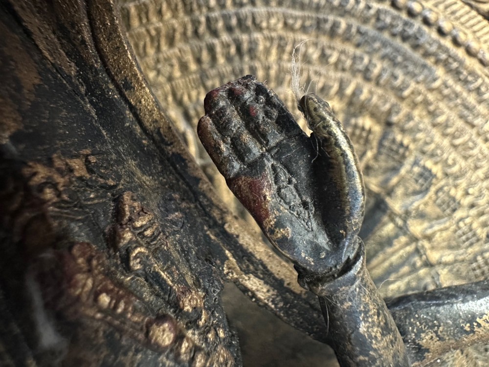 A dark bronze Tibetan sculpture depicting eleven-headed Avalokiteshvara with radiating arms set against a halo mandorla on a lotus pedestal. View XII