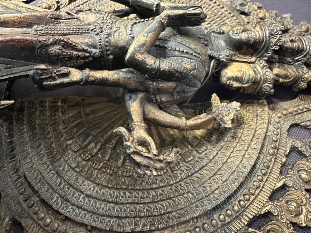 A dark bronze Tibetan sculpture depicting eleven-headed Avalokiteshvara with radiating arms set against a halo mandorla on a lotus pedestal. View XIII