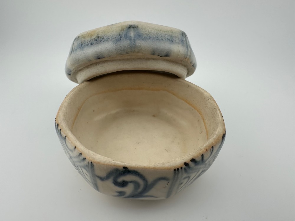 Small octagonal ceramic covered box featuring off-white glaze and hand-painted blue cobalt scroll motifs. View VI