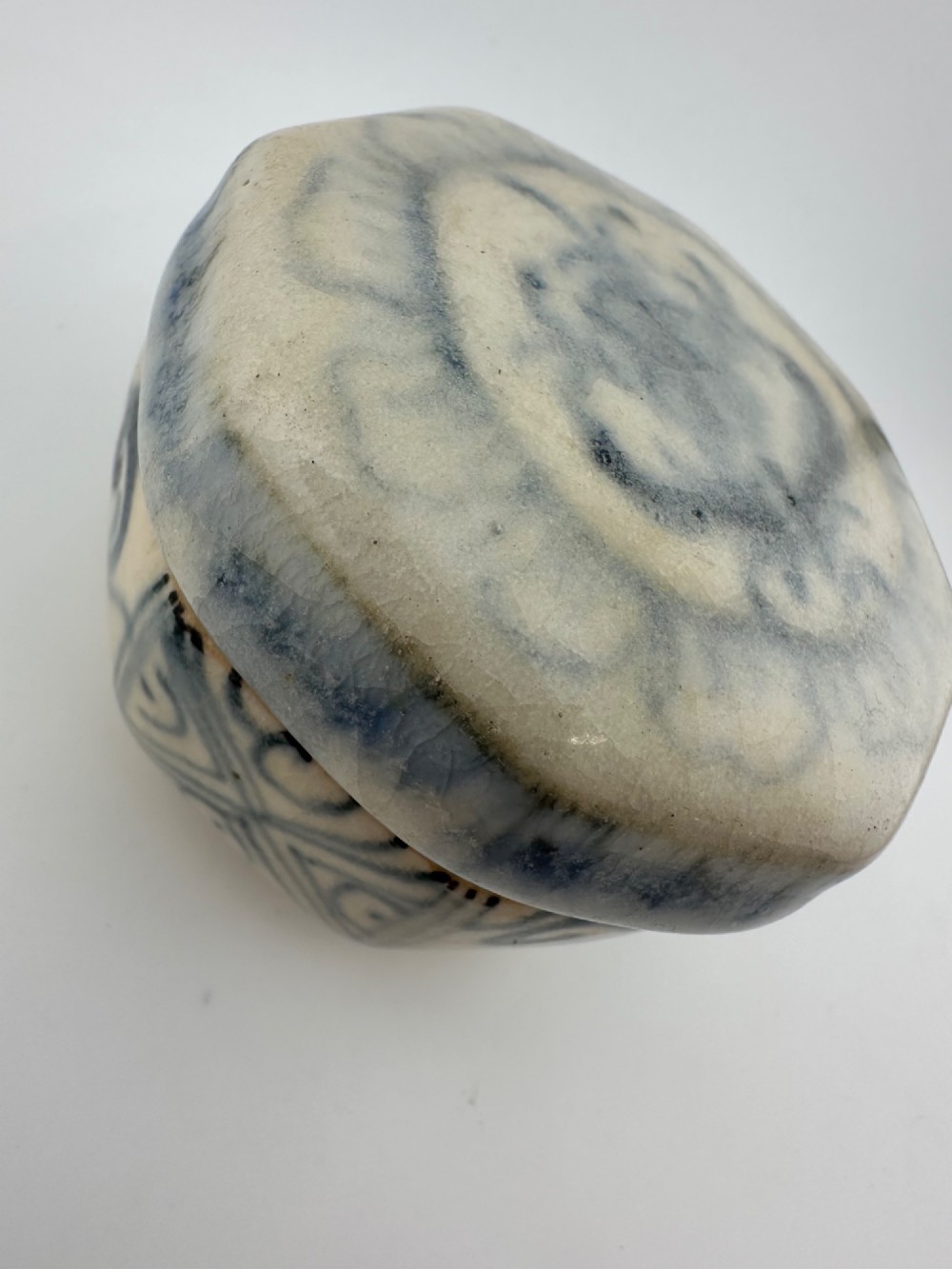 Small octagonal ceramic covered box featuring off-white glaze and hand-painted blue cobalt scroll motifs. View VIII