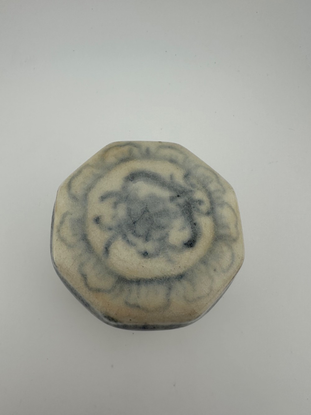 Small octagonal ceramic covered box featuring off-white glaze and hand-painted blue cobalt scroll motifs. View XII