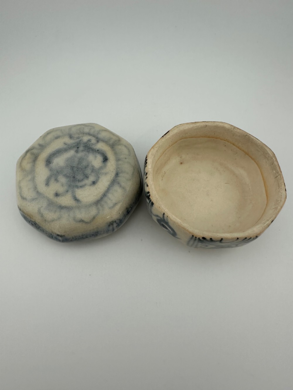 Small octagonal ceramic covered box featuring off-white glaze and hand-painted blue cobalt scroll motifs. View XIII