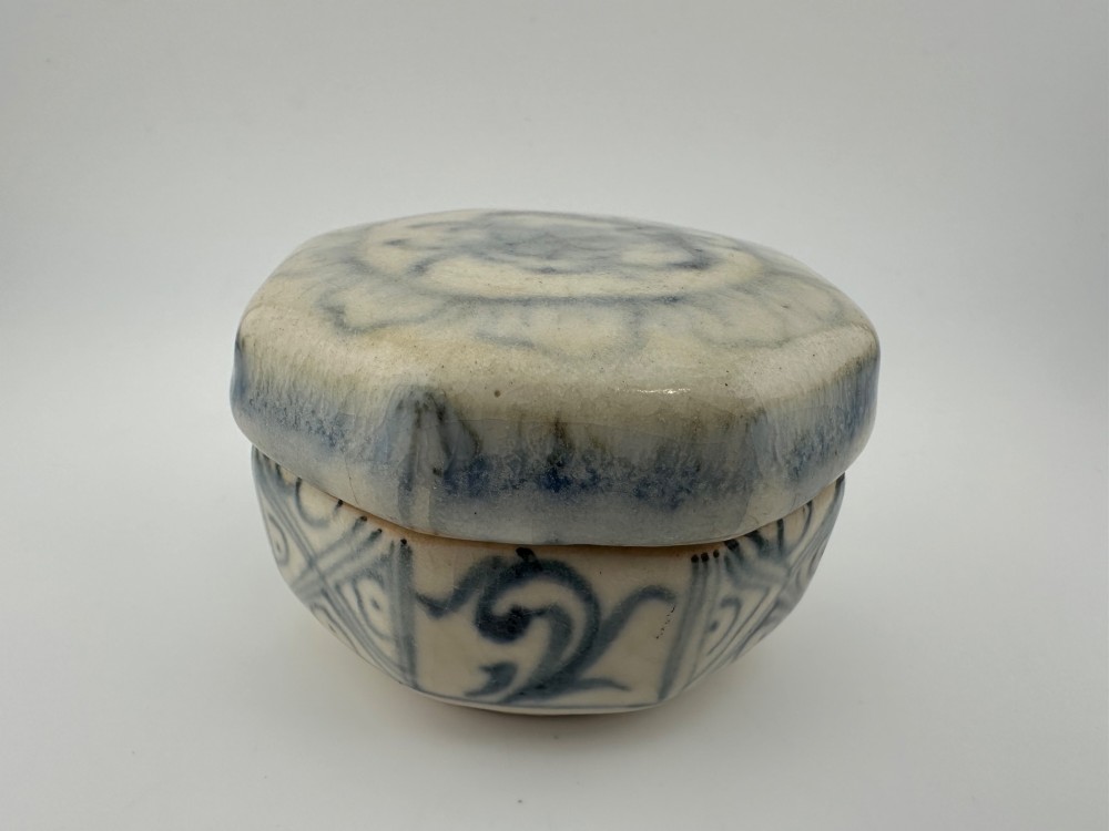Small octagonal ceramic covered box featuring off-white glaze and hand-painted blue cobalt scroll motifs. View XV