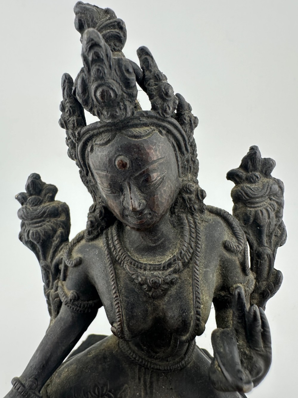 A dark bronze figure of the Buddhist deity Tara seated in lalitasana on an ornate lotus base. View III