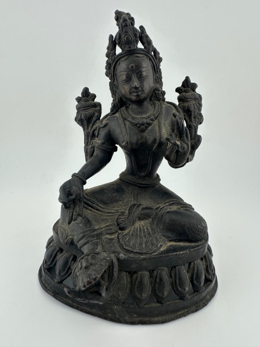 A dark bronze figure of the Buddhist deity Tara seated in lalitasana on an ornate lotus base. View IV