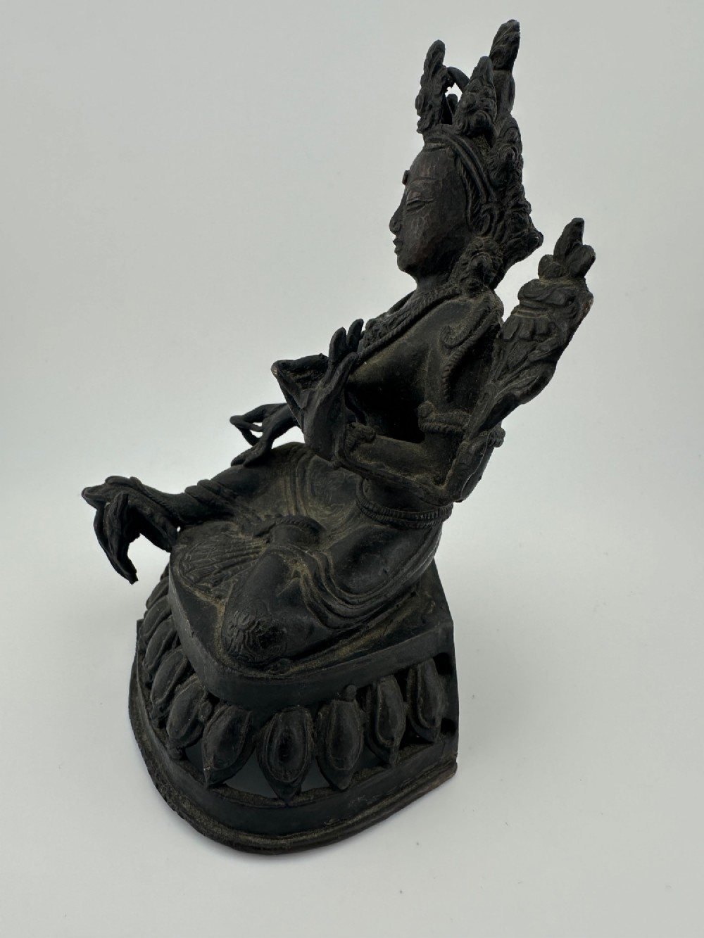 A dark bronze figure of the Buddhist deity Tara seated in lalitasana on an ornate lotus base. View V