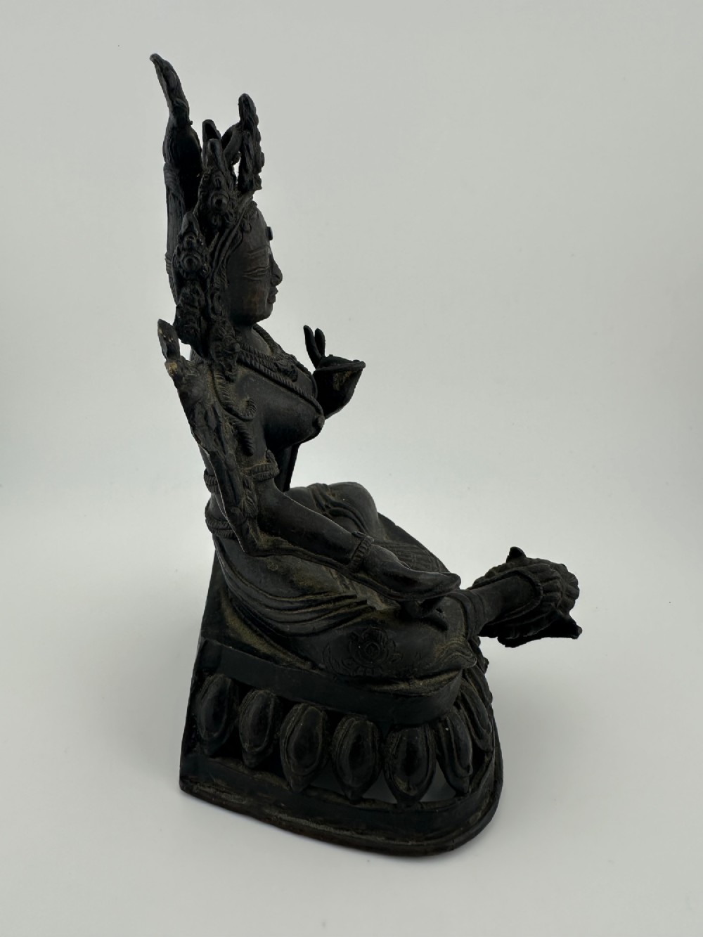 A dark bronze figure of the Buddhist deity Tara seated in lalitasana on an ornate lotus base. View VI