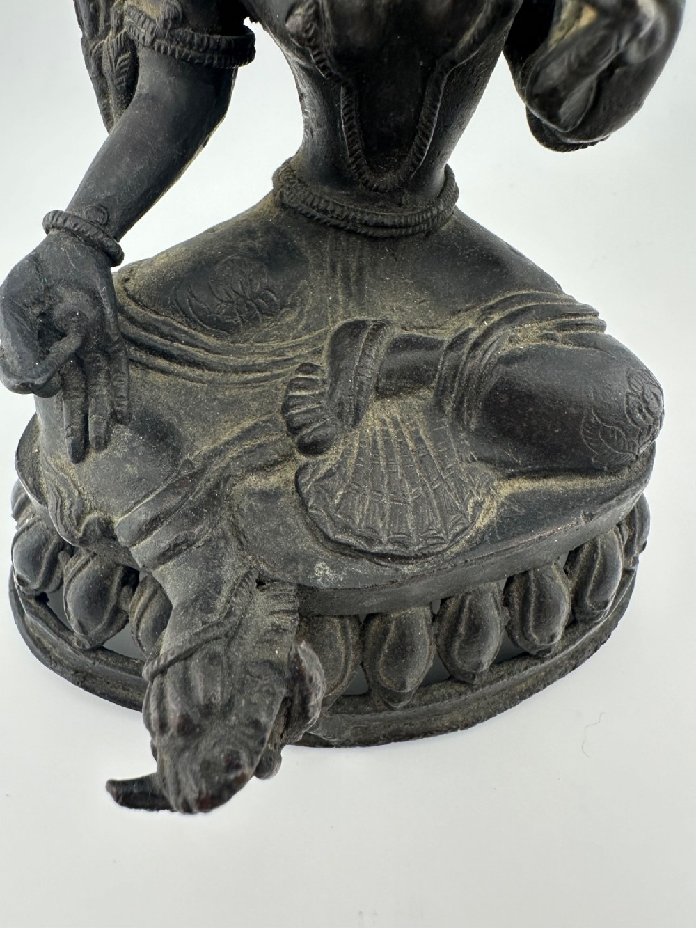 A dark bronze figure of the Buddhist deity Tara seated in lalitasana on an ornate lotus base. View XI