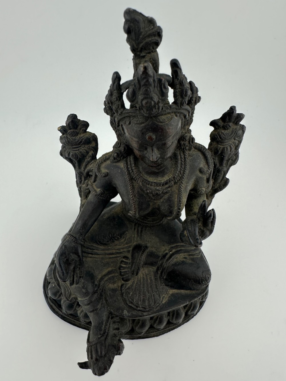 A dark bronze figure of the Buddhist deity Tara seated in lalitasana on an ornate lotus base. View XII