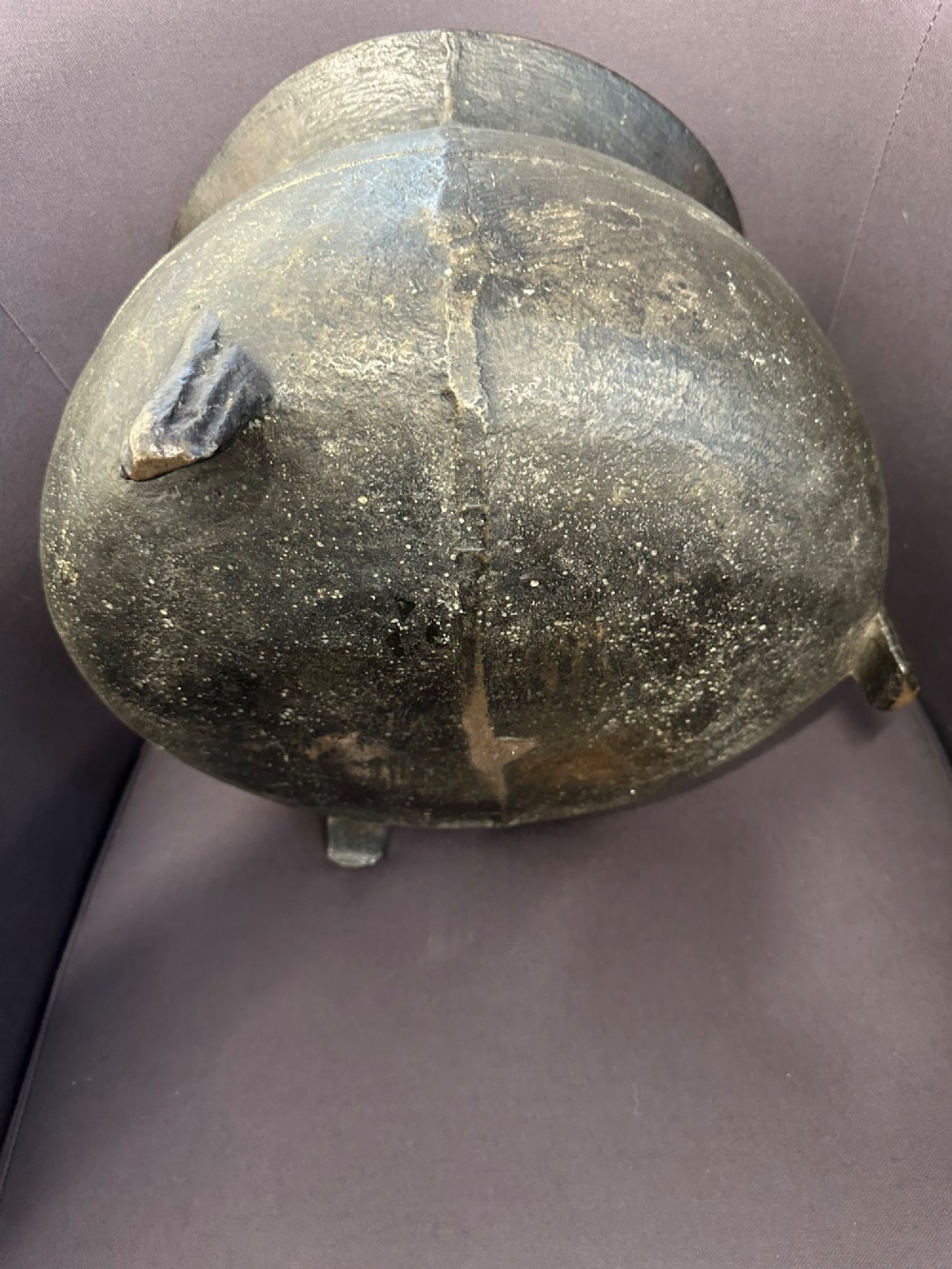 A 17th-century leaded bronze cauldron with a bulbous body, three short feet, angular side handles, and a dark patinated surface. View V