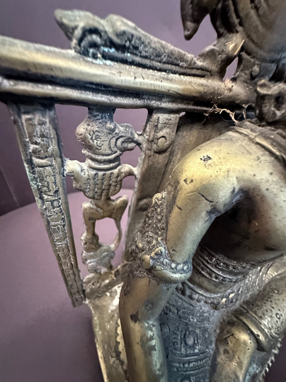An antique cast bronze figure of Green Tara seated on an elaborate throne with a flaming halo backpiece and visible green patination. View IX