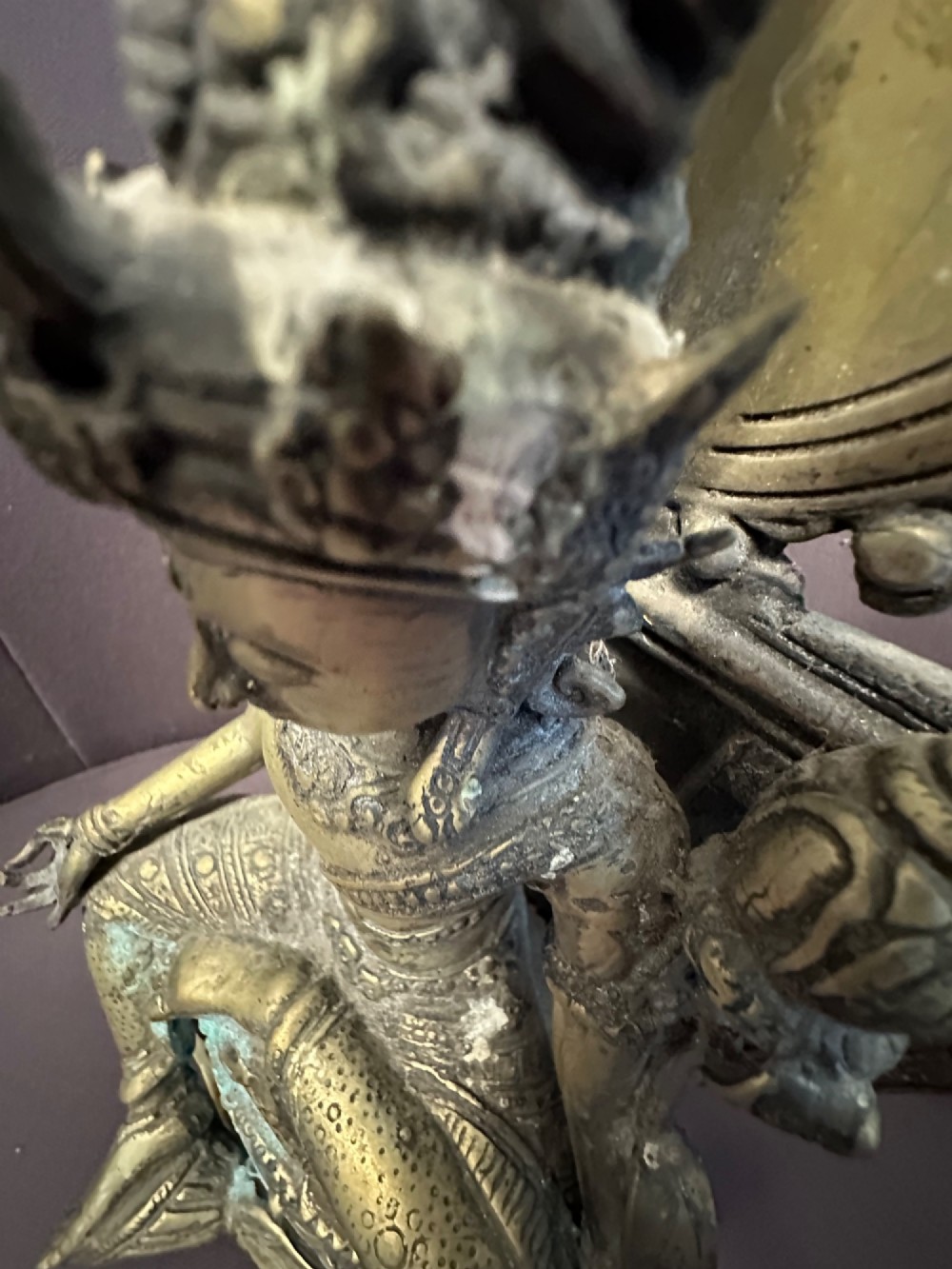 An antique cast bronze figure of Green Tara seated on an elaborate throne with a flaming halo backpiece and visible green patination. View X