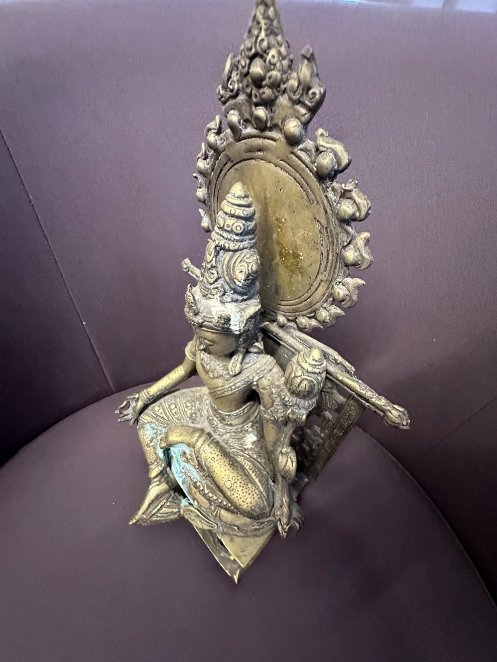 An antique cast bronze figure of Green Tara seated on an elaborate throne with a flaming halo backpiece and visible green patination. View XII