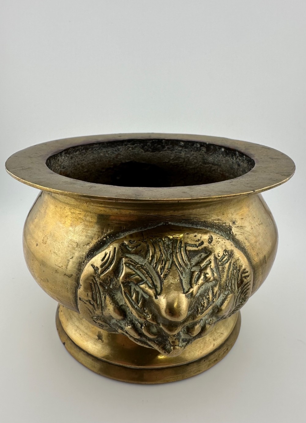 A rounded antique brass Chinese censer featuring a flared rim, pedestal base, and sculpted lion mask handles on either side. View IV
