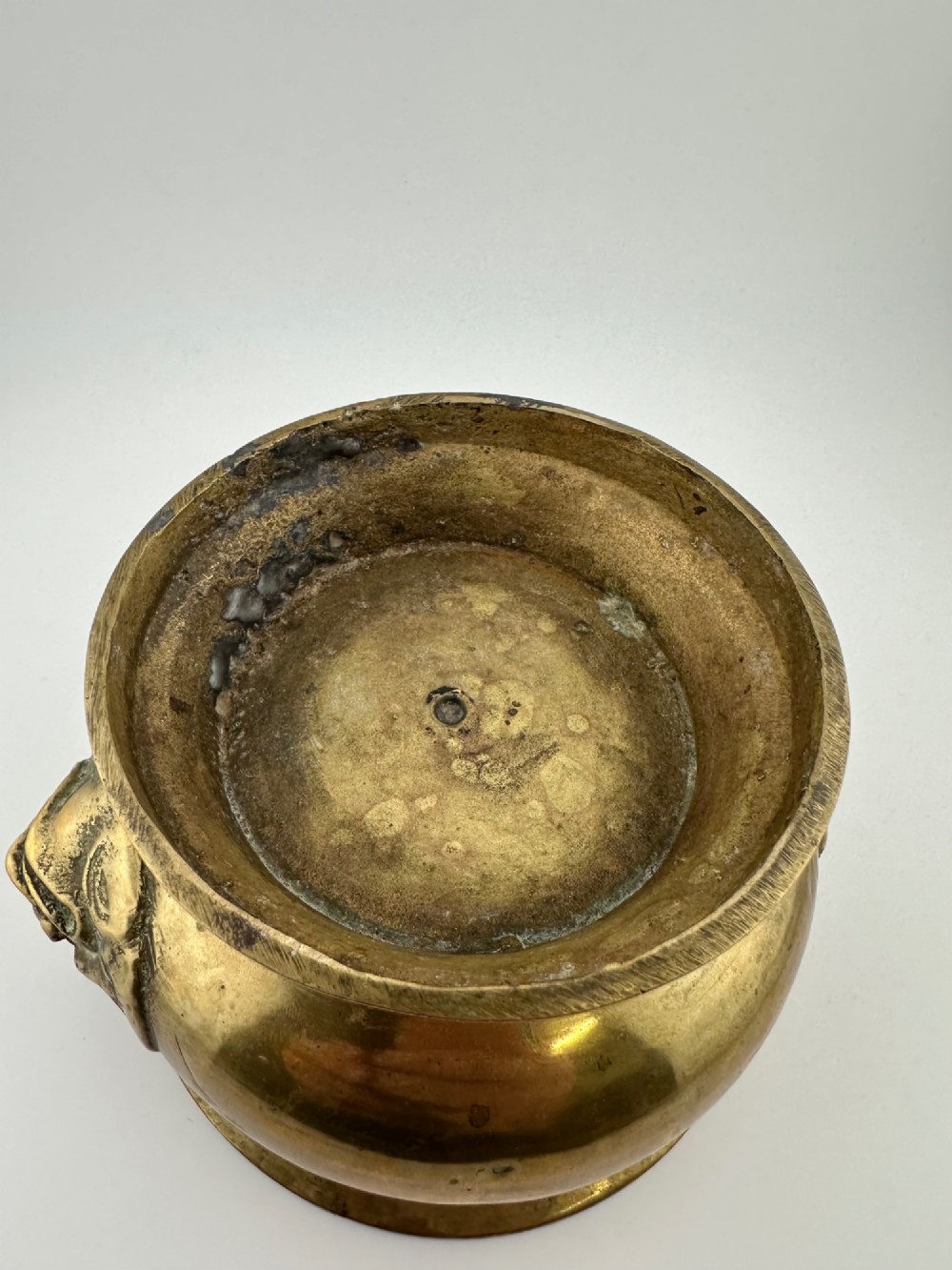 A rounded antique brass Chinese censer featuring a flared rim, pedestal base, and sculpted lion mask handles on either side. View VIII