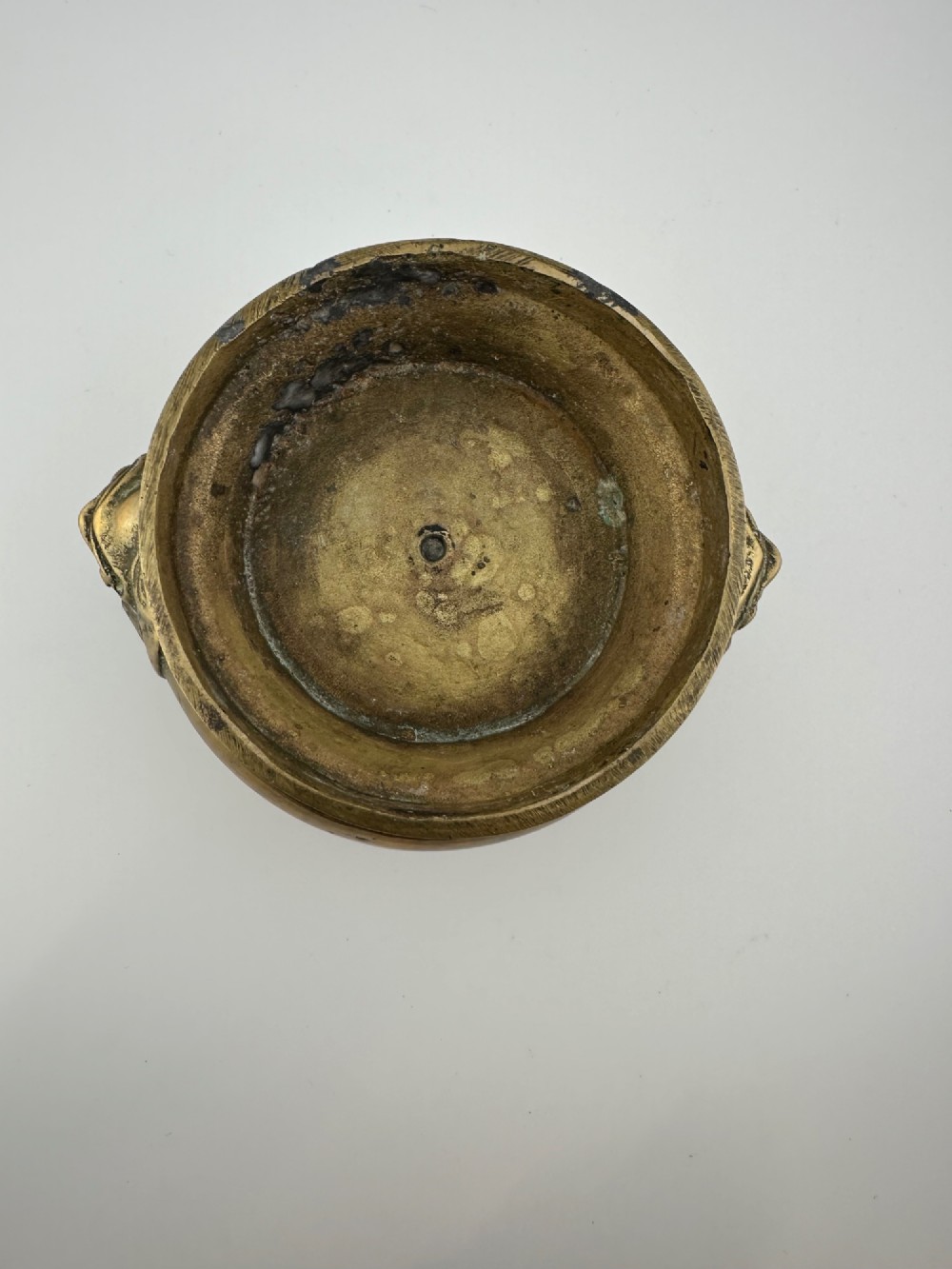 A rounded antique brass Chinese censer featuring a flared rim, pedestal base, and sculpted lion mask handles on either side. View X