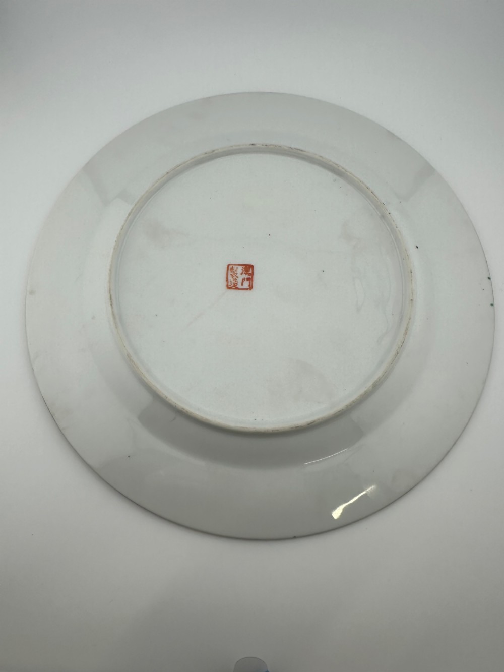 A circular hand-painted ceramic charger with alternating panels depicting human figures and floral motifs in green, pink, and red enamels with gold accents. View V