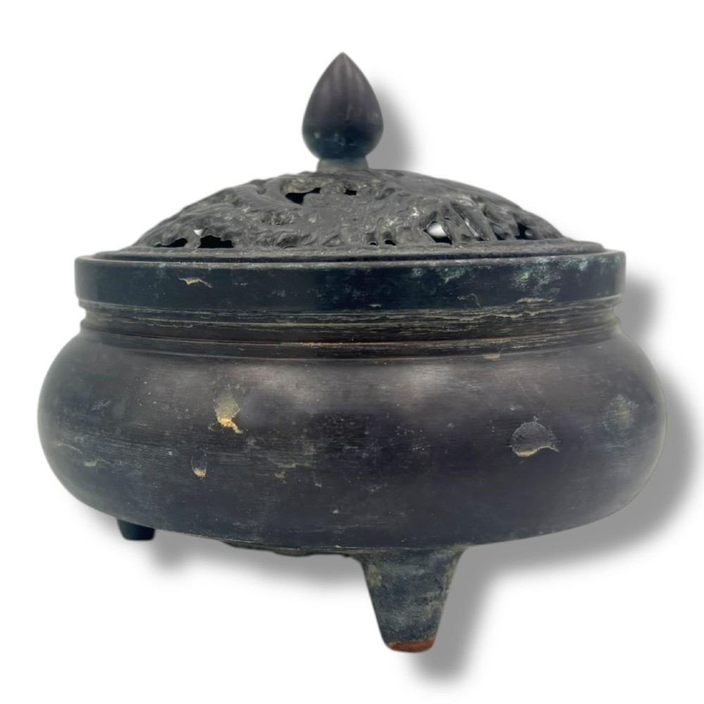 A dark patinated bronze tripod censer featuring a rounded body, three short tapered feet, and a pierced openwork lid topped with a bud finial. View II