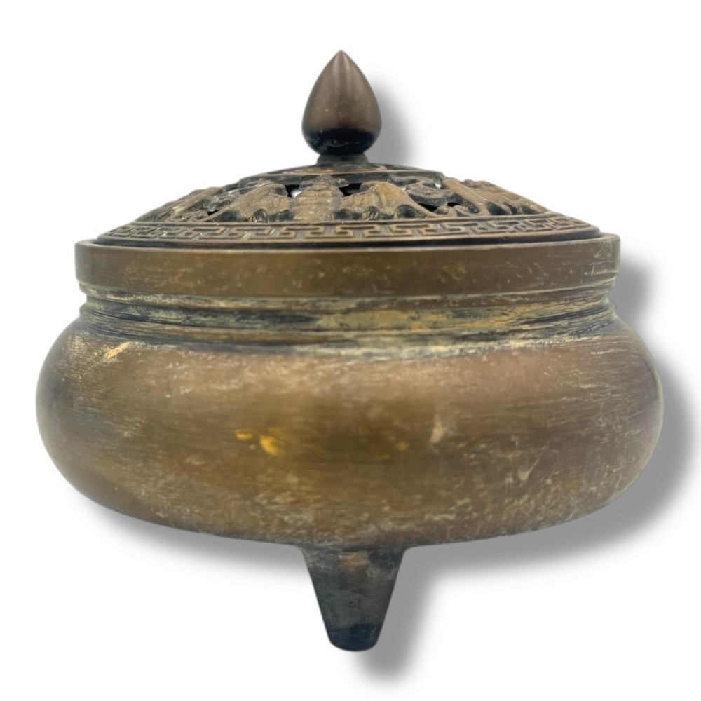 A Chinese bronze tripod censer featuring a compressed circular body, three tapered feet, and a reticulated lotus lid topped with a pointed finial. View II