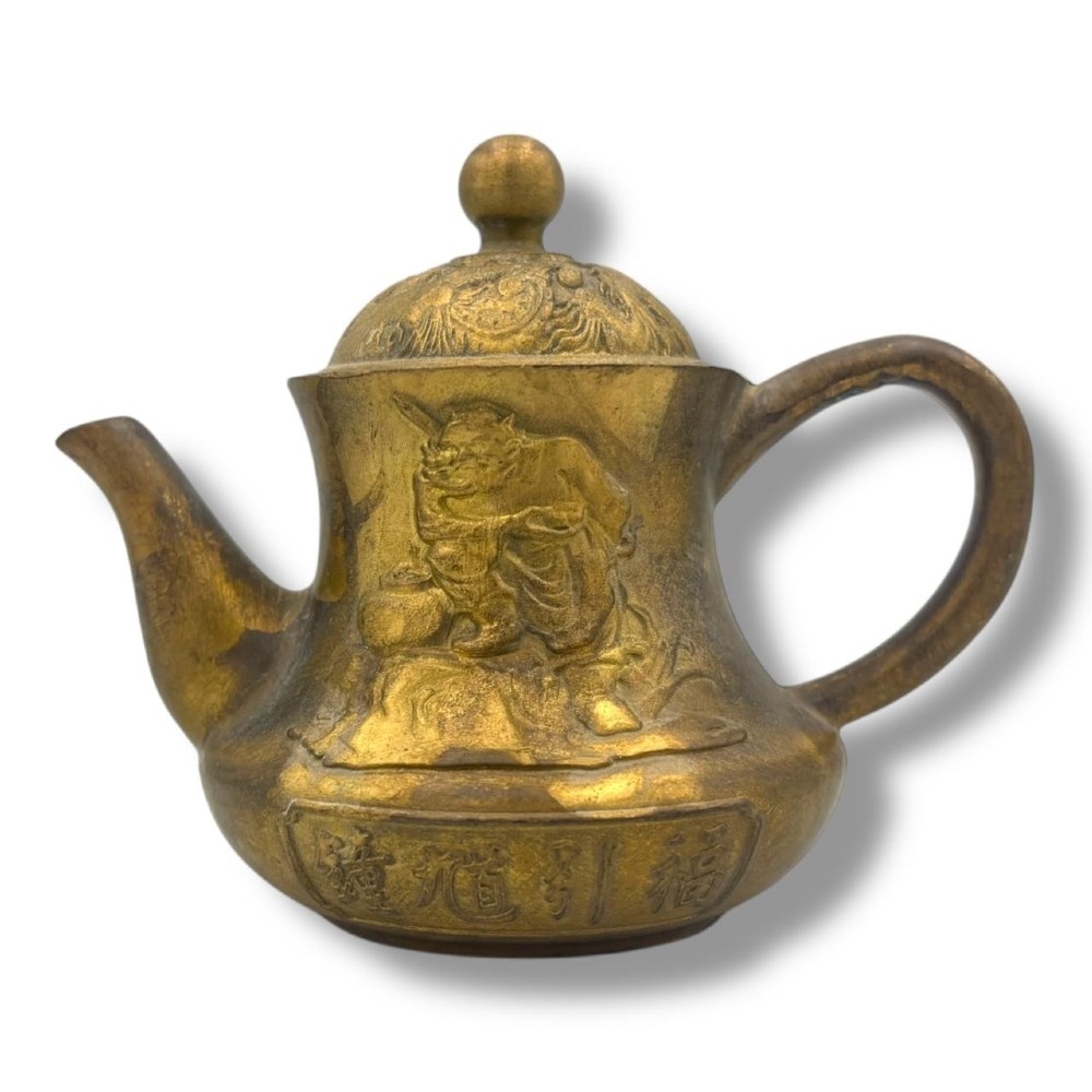 A cast brass Chinese teapot featuring raised relief figures, traditional Chinese characters along the base, a curved spout, handle, and a round lid knob. View VIII