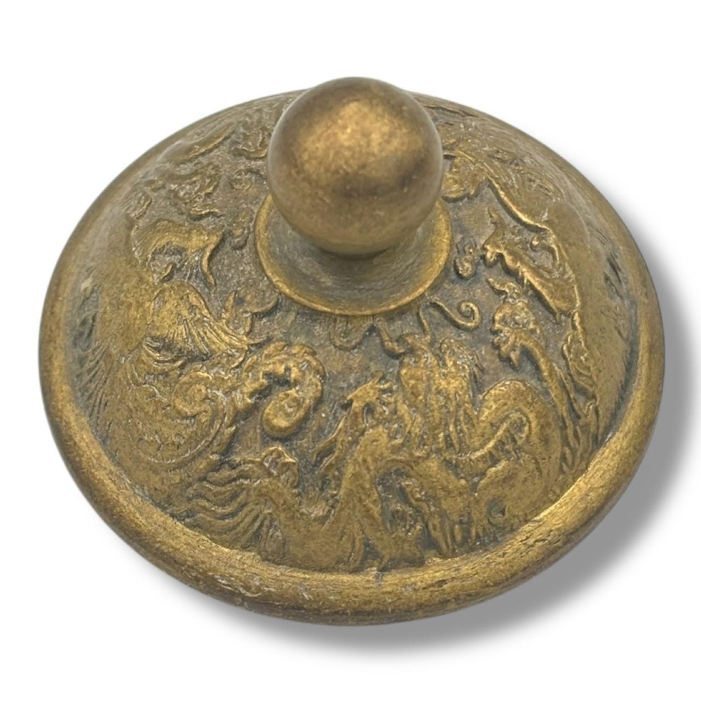 A cast brass Chinese teapot featuring raised relief figures, traditional Chinese characters along the base, a curved spout, handle, and a round lid knob. View XI