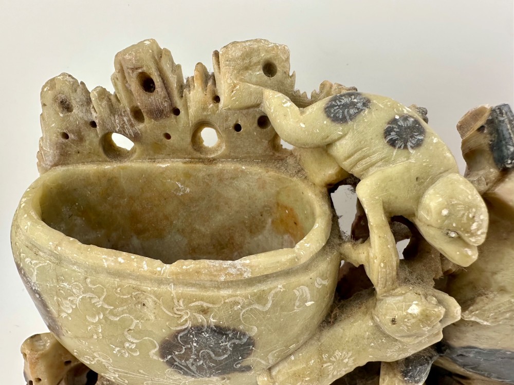 An antique Chinese carved soapstone double brush washer featuring two vessel shapes supported by carved animals and pierced rockwork in shades of mottled green, cream, and dark grey. View III