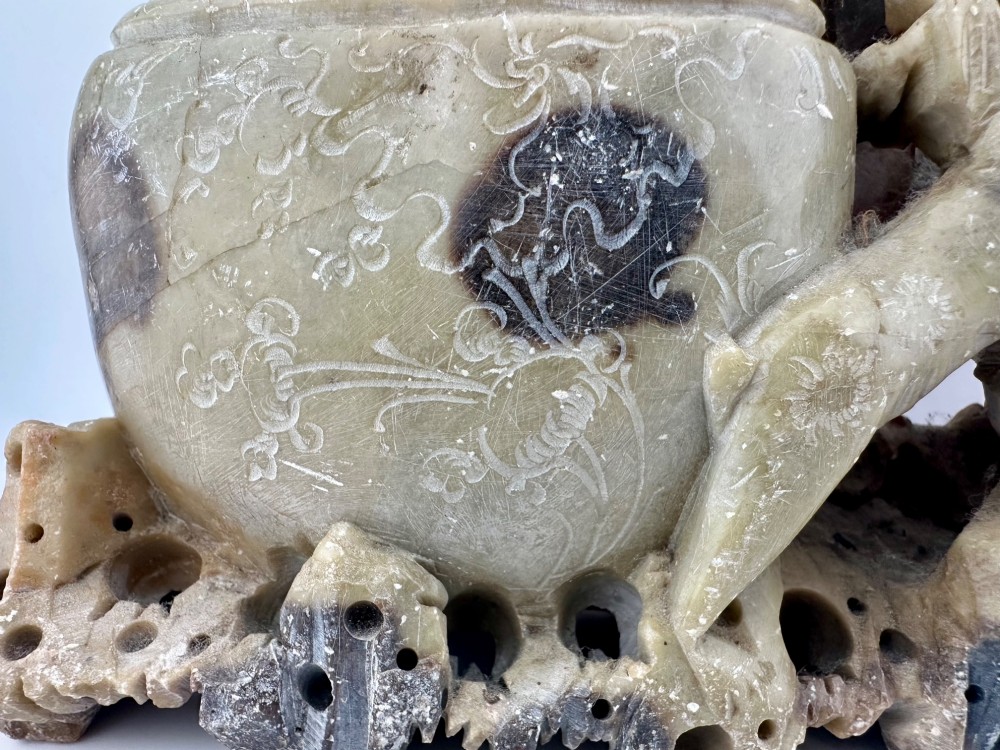 An antique Chinese carved soapstone double brush washer featuring two vessel shapes supported by carved animals and pierced rockwork in shades of mottled green, cream, and dark grey. View V