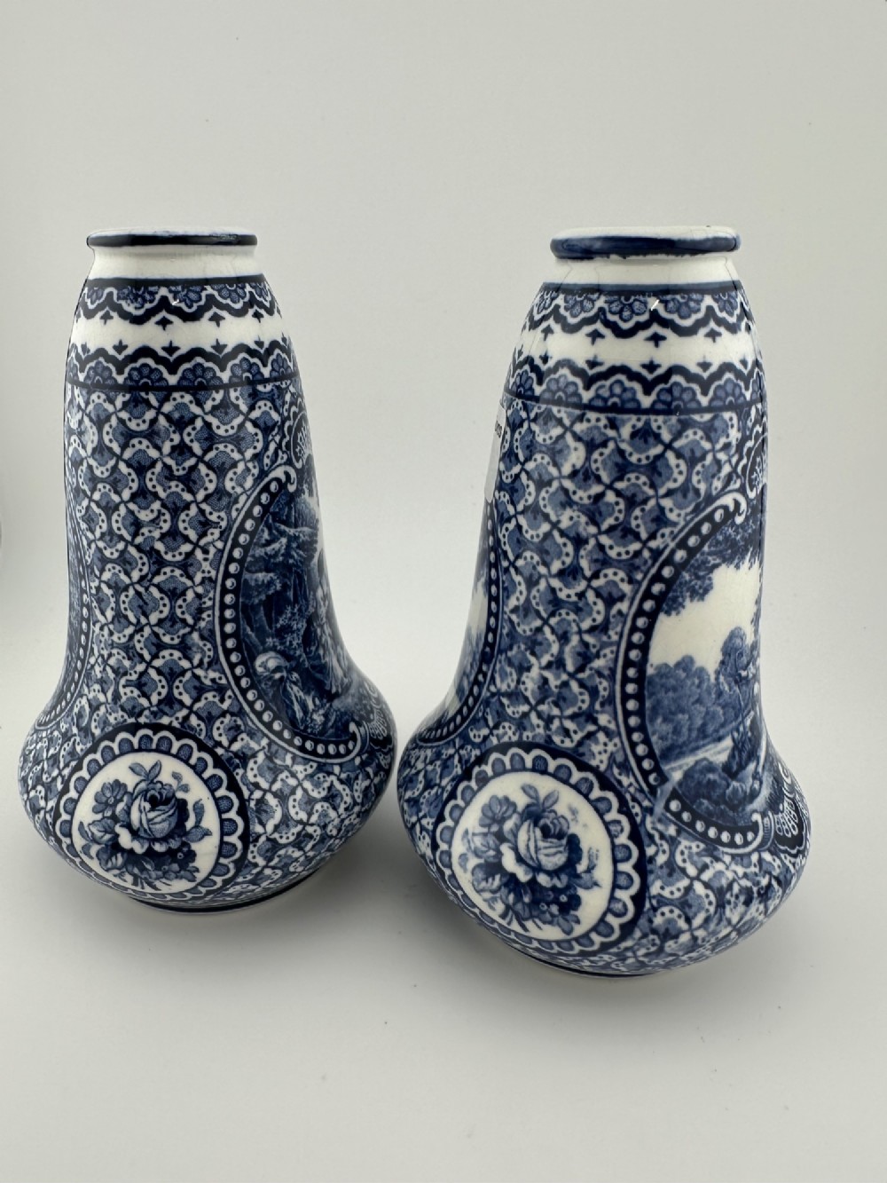 A pair of antique blue and white ceramic vases featuring central pastoral vignettes framed by elaborate scrollwork patterns. View III