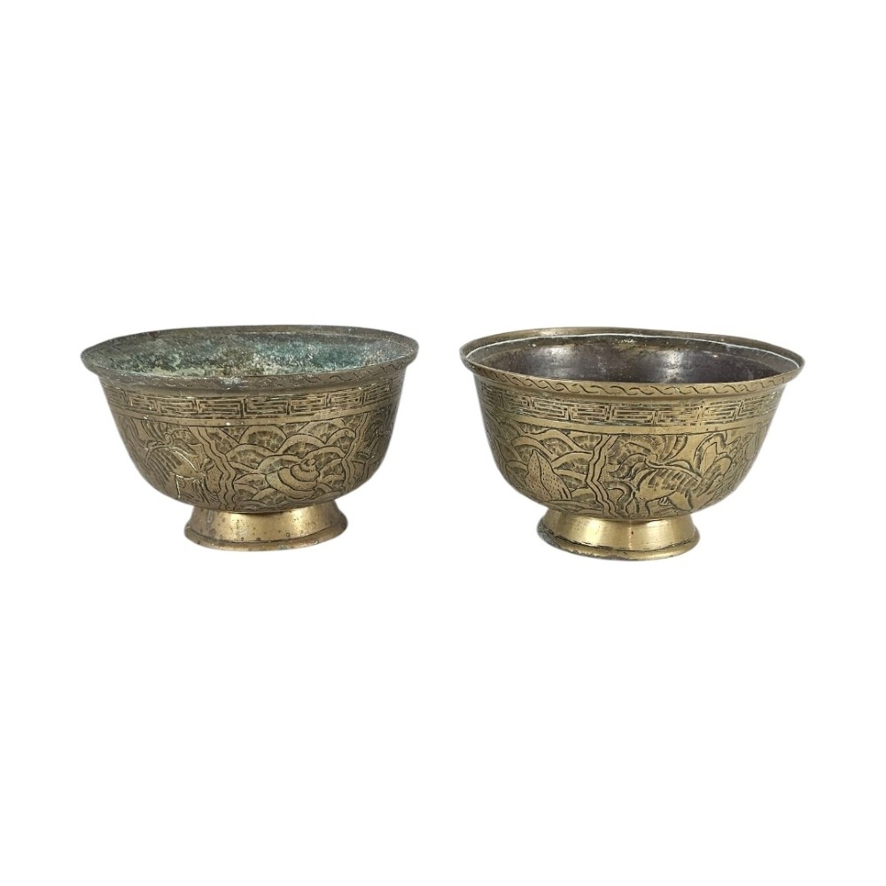 A pair of antique Chinese cast bronze footed bowls decorated with etched bird and lotus leaf motifs beneath key-fret rim borders.