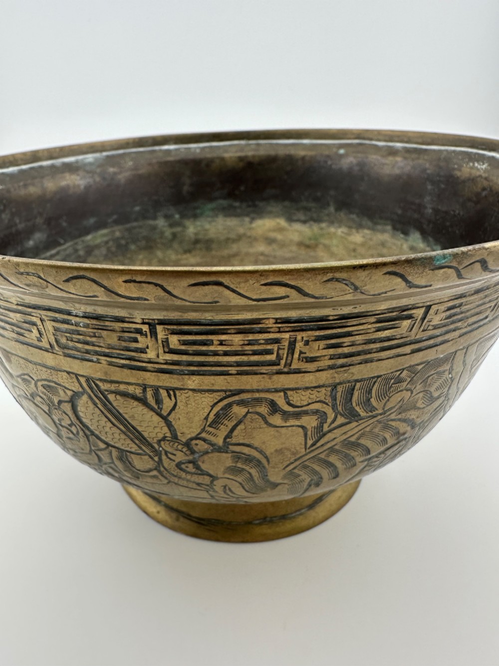 A pair of antique Chinese cast bronze footed bowls decorated with etched bird and lotus leaf motifs beneath key-fret rim borders. View VII