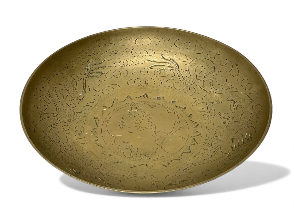 A circular shallow brass dish featuring detailed hand-engraved designs of dragons, clouds, and a central circular motif.