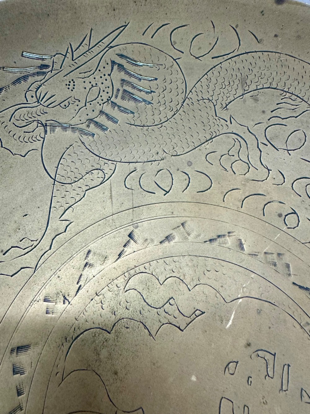 A circular shallow brass dish featuring detailed hand-engraved designs of dragons, clouds, and a central circular motif. View V
