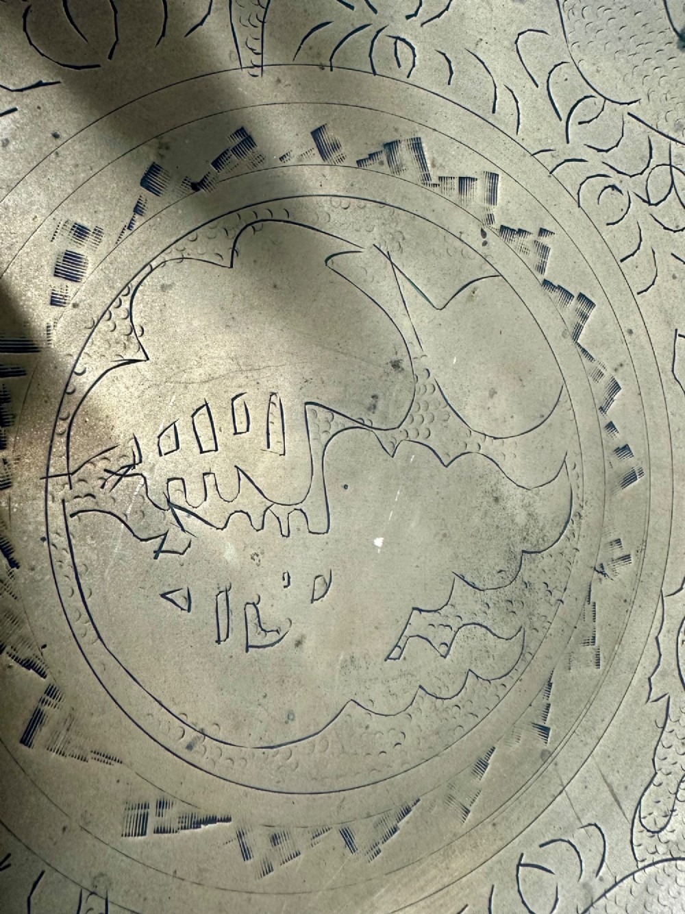 A circular shallow brass dish featuring detailed hand-engraved designs of dragons, clouds, and a central circular motif. View VI