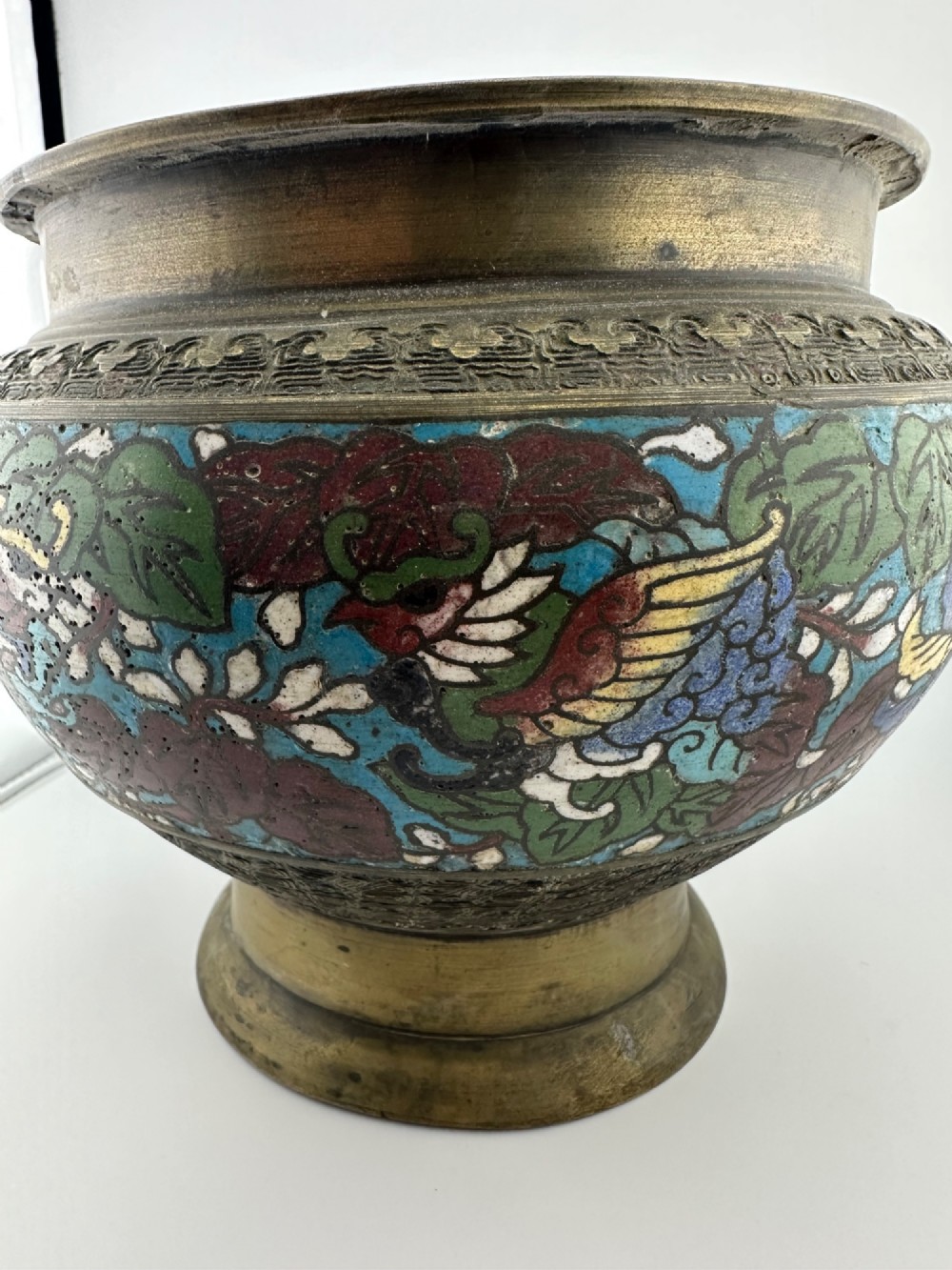 A set of three bulbous antique Chinese bronze jardinieres featuring colourful champleve enamel floral decoration around their midsections. View IV