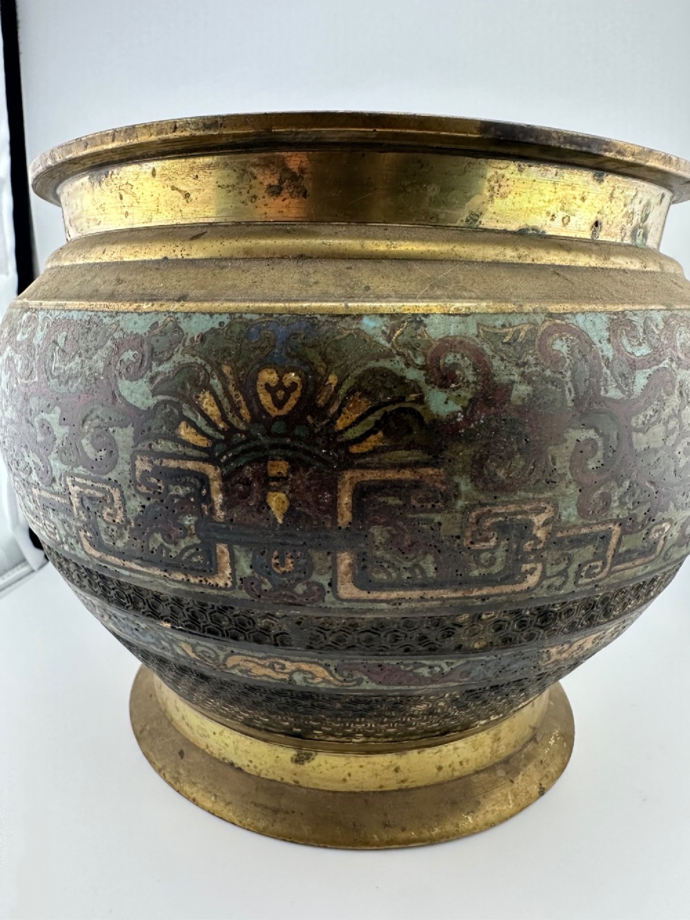 A set of three bulbous antique Chinese bronze jardinieres featuring colourful champleve enamel floral decoration around their midsections. View V