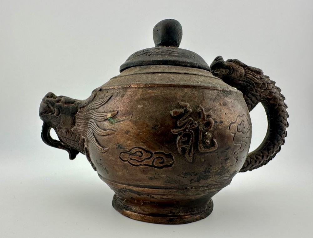 A dark cast bronze Chinese teapot featuring a sculpted dragon handle, a dragon-head spout, and raised Chinese character carvings on the main body. View II