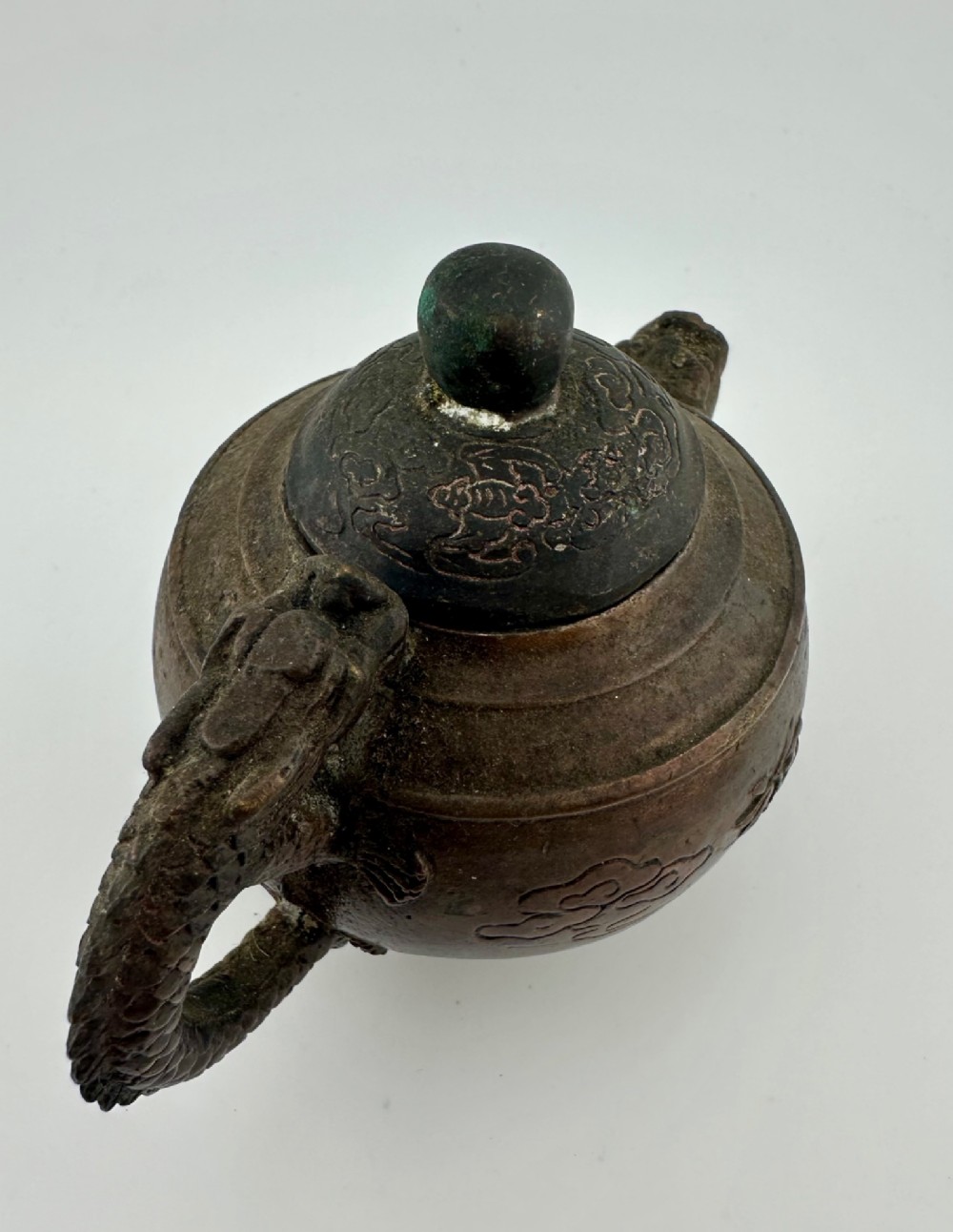 A dark cast bronze Chinese teapot featuring a sculpted dragon handle, a dragon-head spout, and raised Chinese character carvings on the main body. View IV