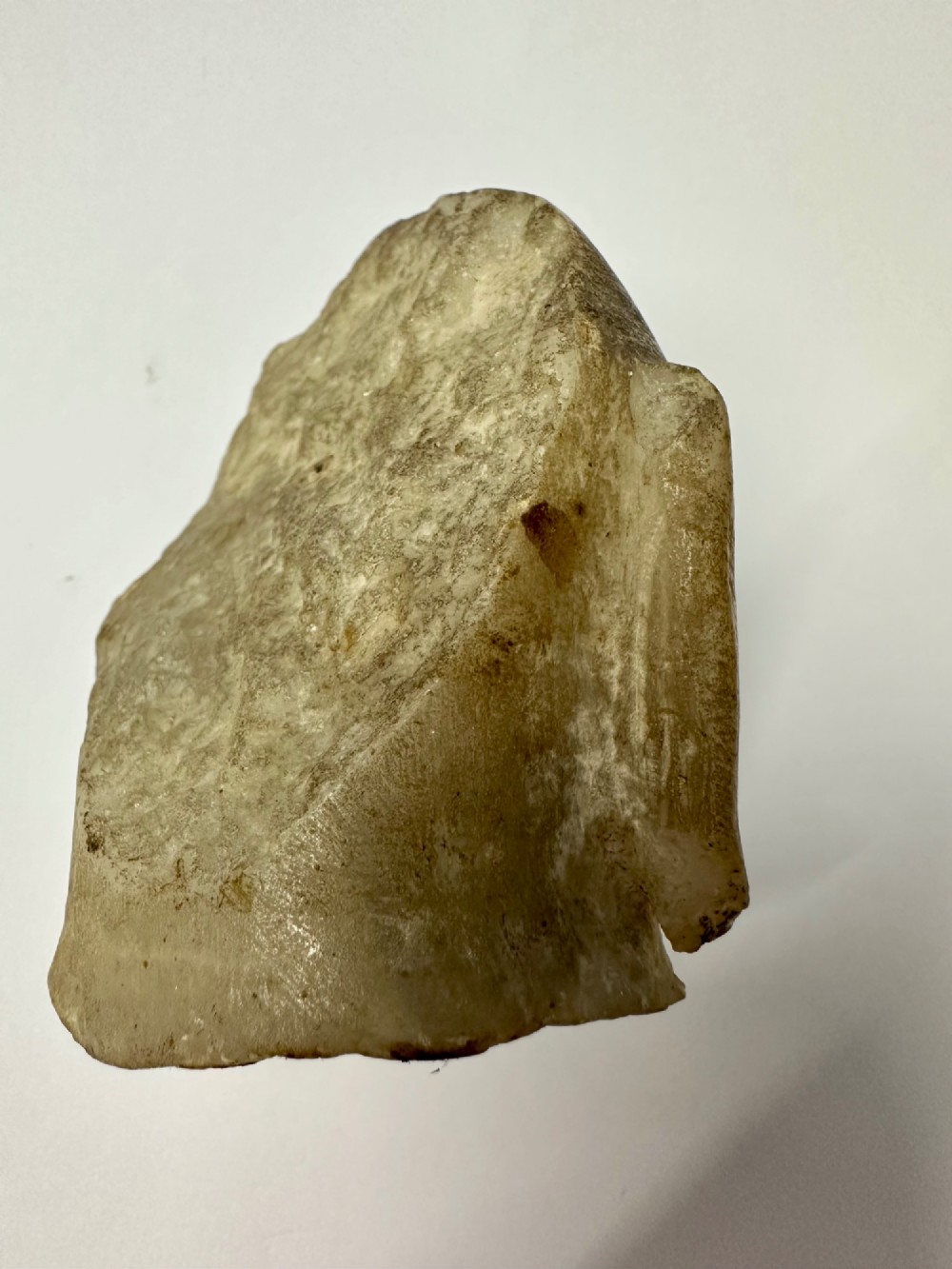 A carved off-white hardstone head fragment featuring facial features, elongated earlobes, and faint traces of gilding across the surface. View VI