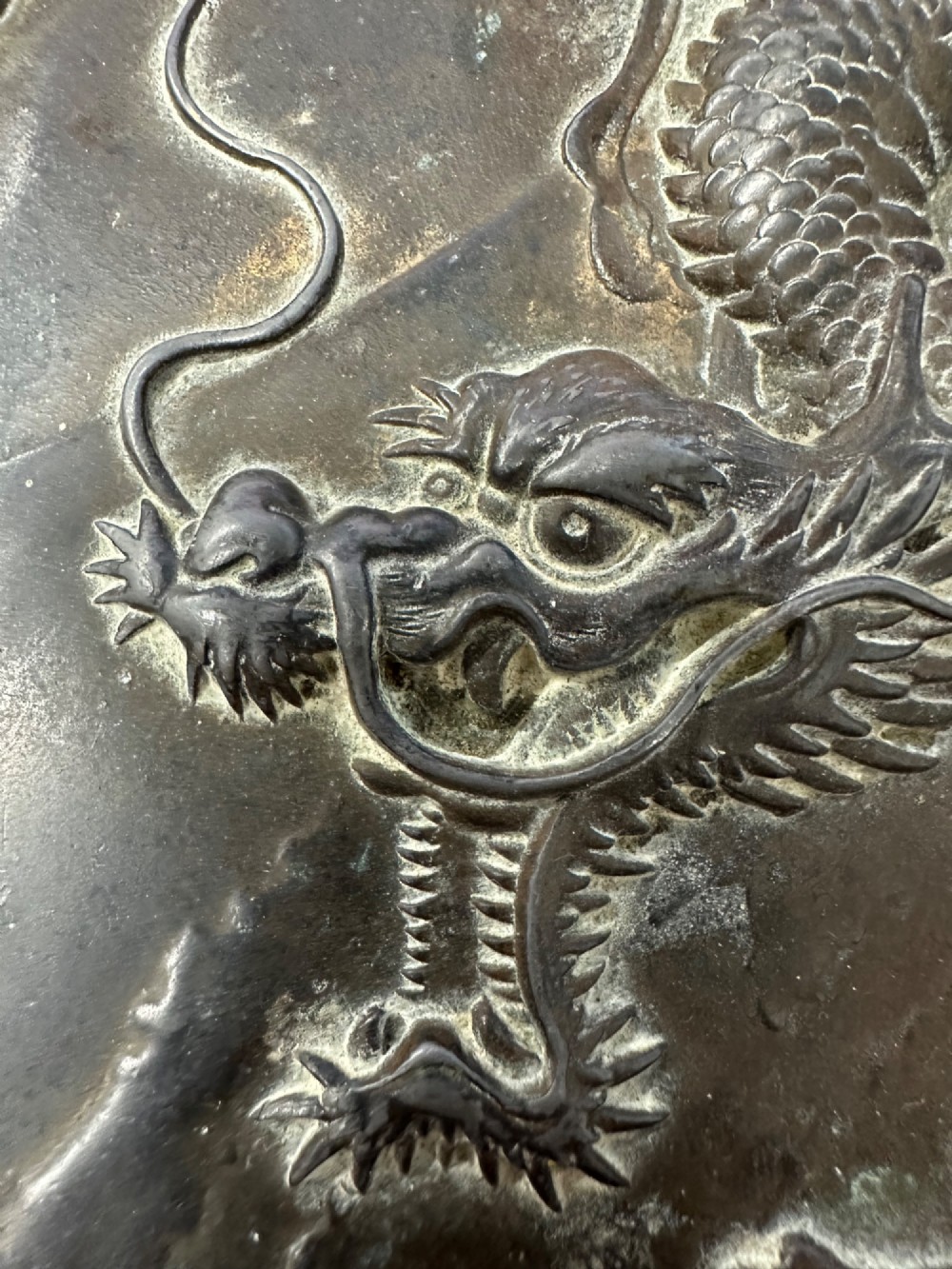 A dark patinated metal tray featuring a raised relief carving of a Japanese dragon coiling around its organic rim. View VI