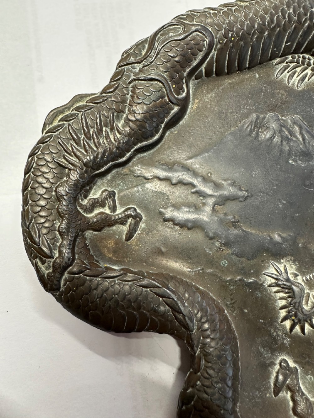 A dark patinated metal tray featuring a raised relief carving of a Japanese dragon coiling around its organic rim. View VII