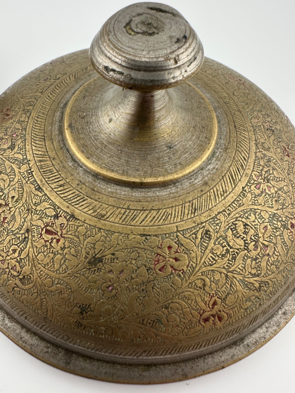 An antique domed Indian brass hand gong with detailed floral engravings, a turned central finial handle, and a dark wooden striker. View IV