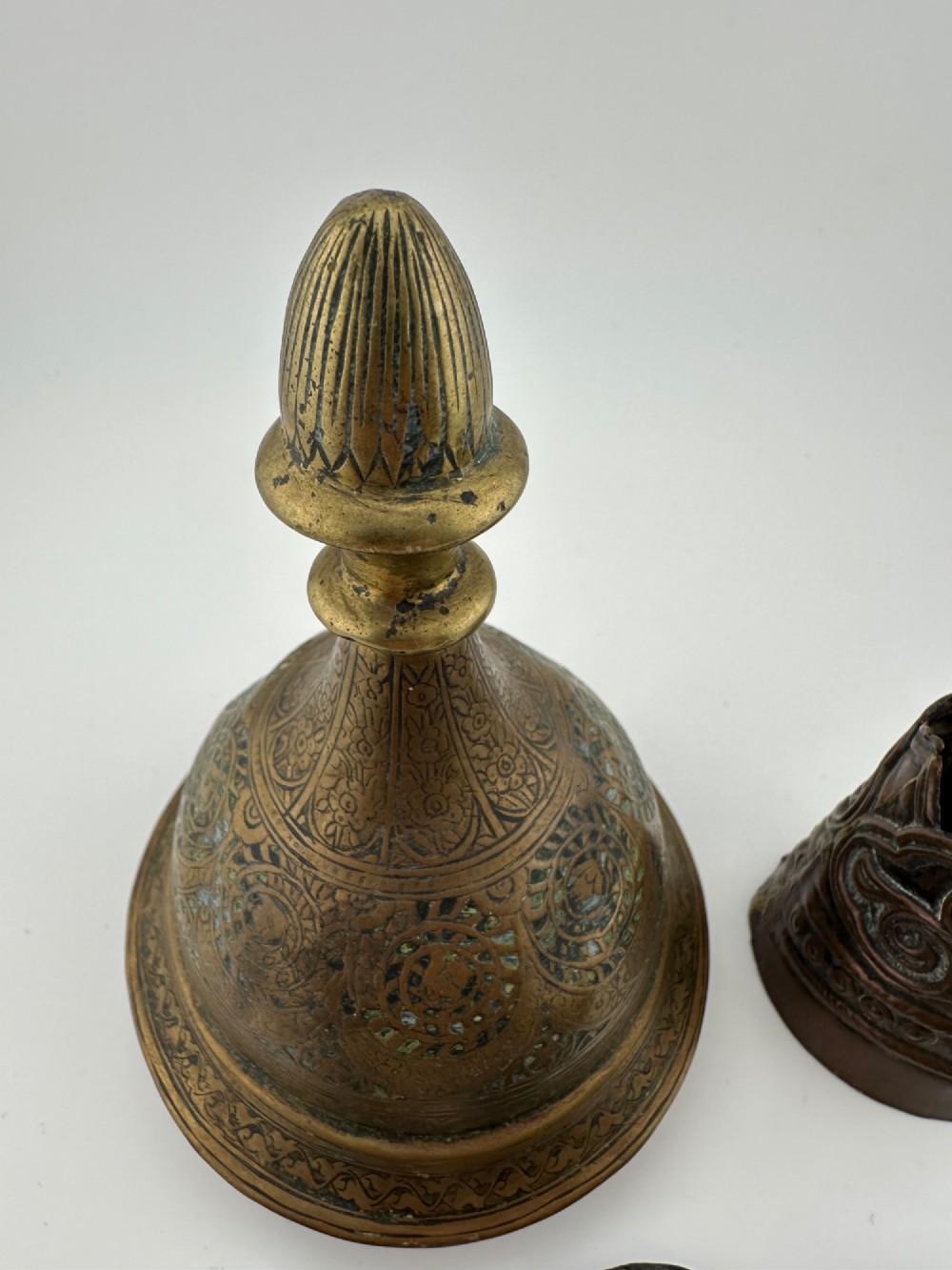 A five-piece group of antique Persian Qajar metalware, including an engraved brass incense burner lid with a finial, a dark carved vessel collar, and three small circular lids. View III