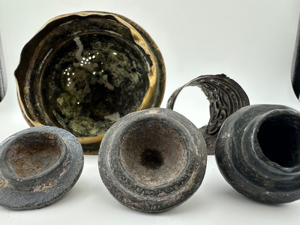 A five-piece group of antique Persian Qajar metalware, including an engraved brass incense burner lid with a finial, a dark carved vessel collar, and three small circular lids. View VIII