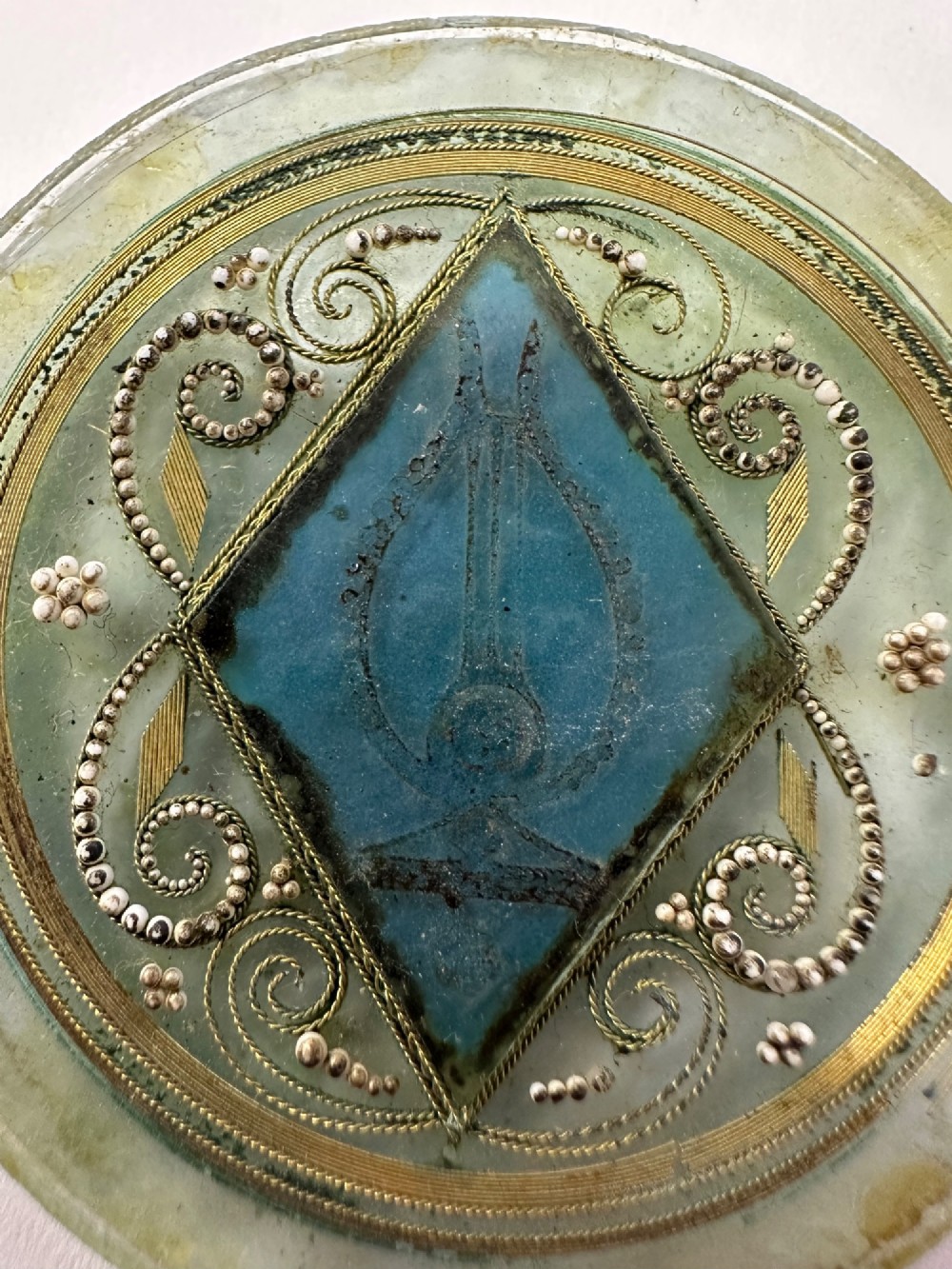 A circular glass Ottoman roundel featuring delicate gilt filigree scrollwork and a central diamond-shaped blue medallion with a calligraphic tughra. View II