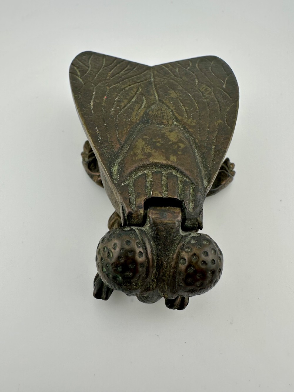 A cast dark brass match holder sculpted in the detailed shape of a fly with textured wings, compound eyes, and six legs. View II