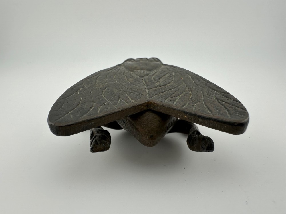 A cast dark brass match holder sculpted in the detailed shape of a fly with textured wings, compound eyes, and six legs. View VII