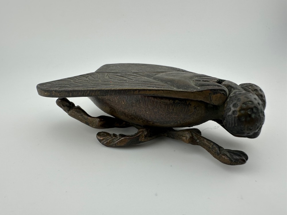 A cast dark brass match holder sculpted in the detailed shape of a fly with textured wings, compound eyes, and six legs. View IX